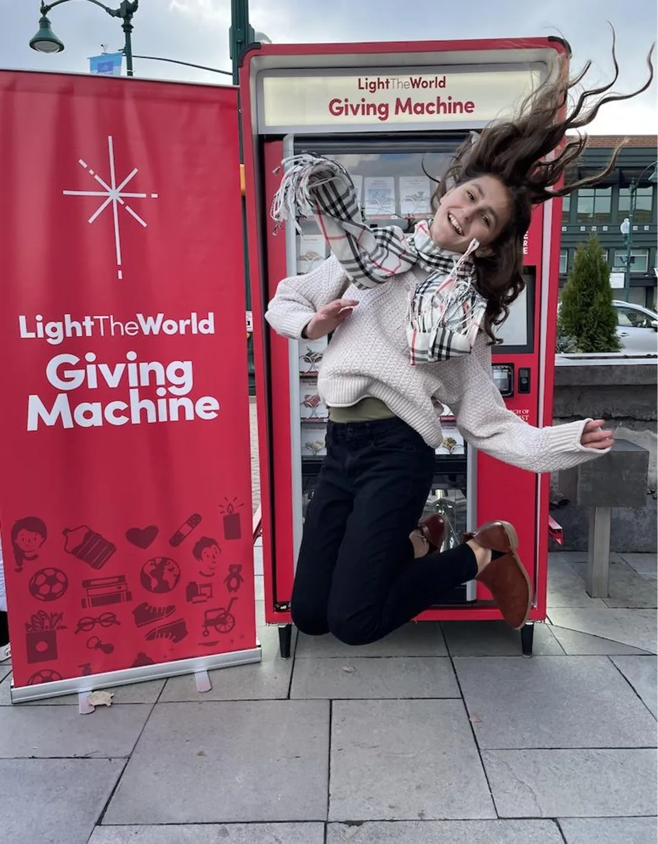 A visitor jumps for joy beside the red Giving Machine in Indiana